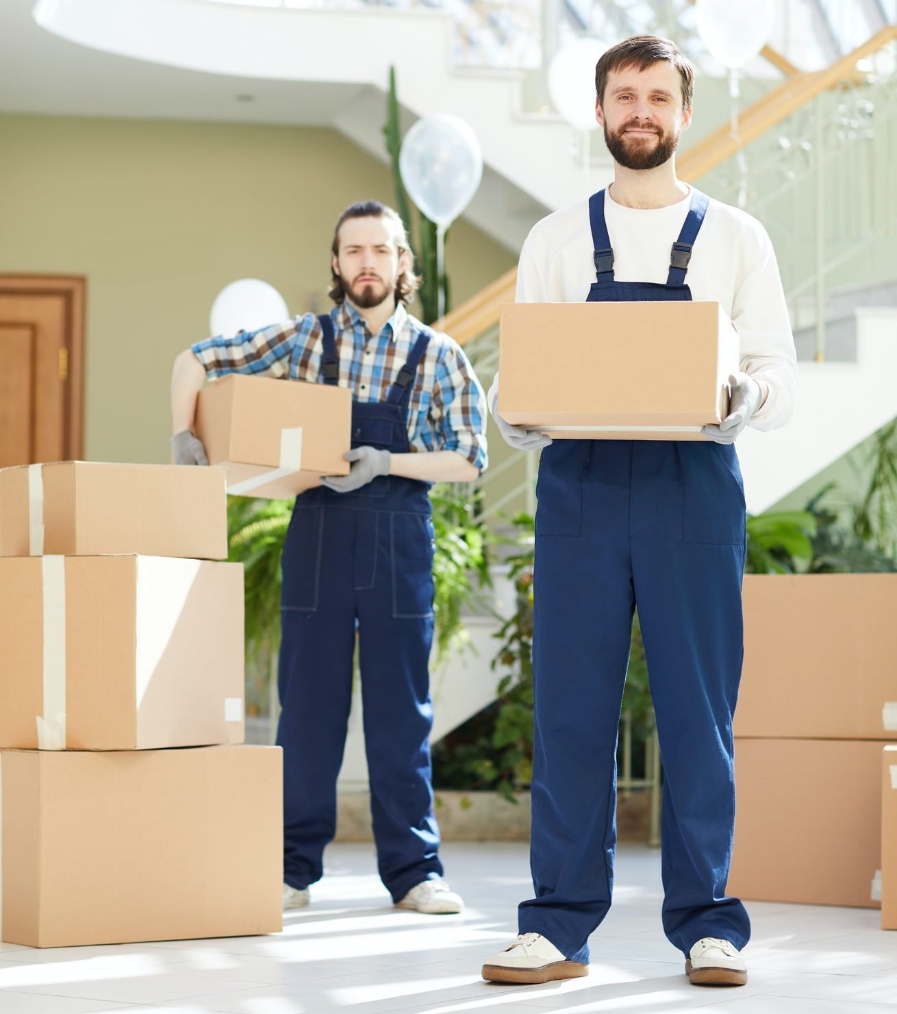 Two movers carrying packed boxes inside a home